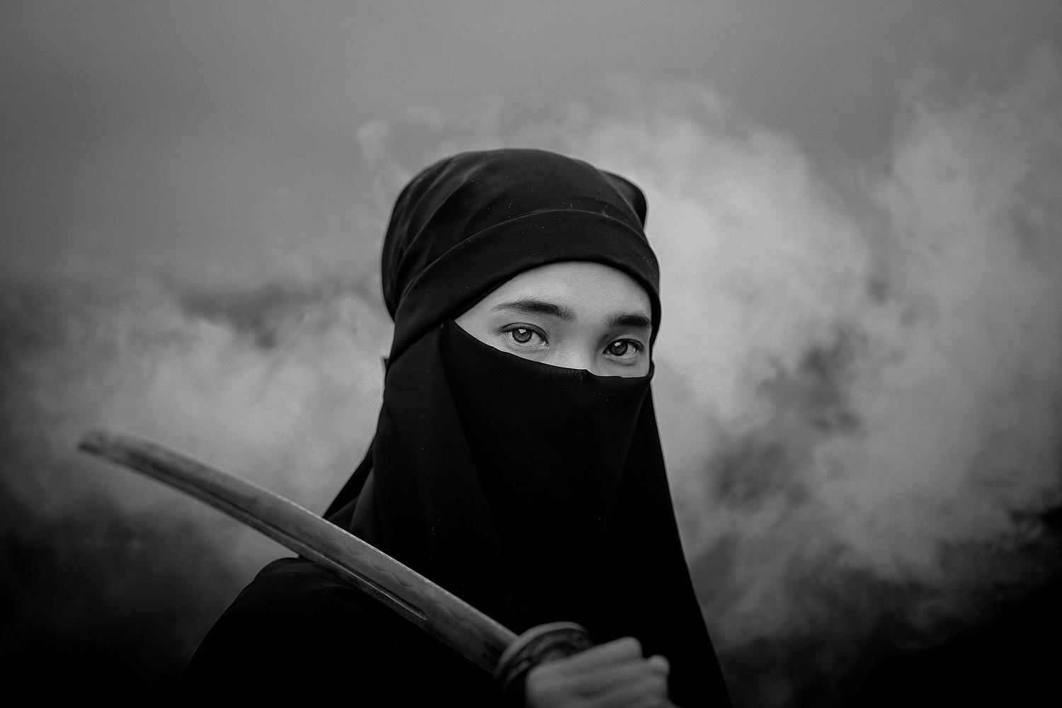 Retrato en blanco y negro de un guerrero ninja emergiendo de la niebla, representando el sigilo y el misterio en el Japón feudal.