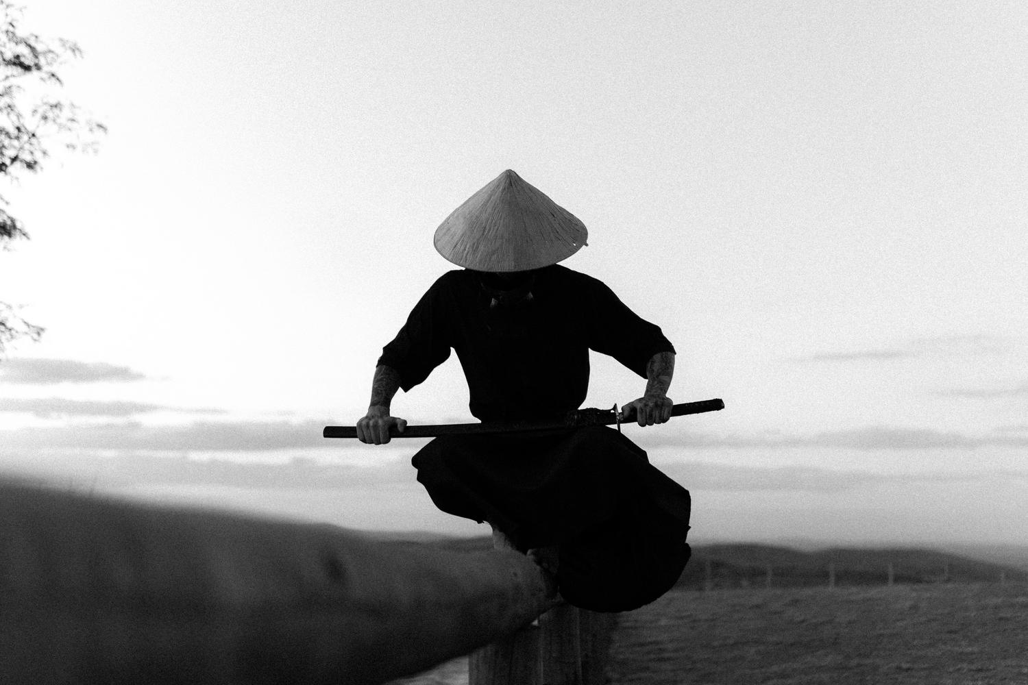 Silueta de un samurái con katana durante el atardecer, evocando un sentimiento de calma, enfoque y destino.