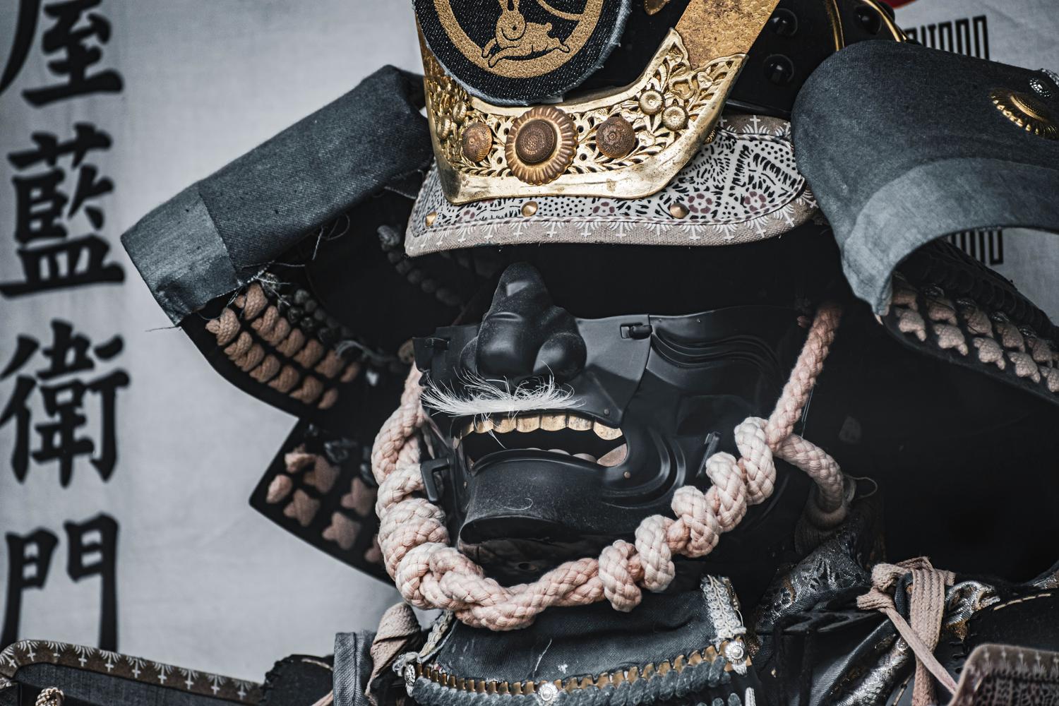 Primer plano detallado de una armadura y casco de samurái tradicional, destacando la artesanía y el diseño del periodo feudal japonés.