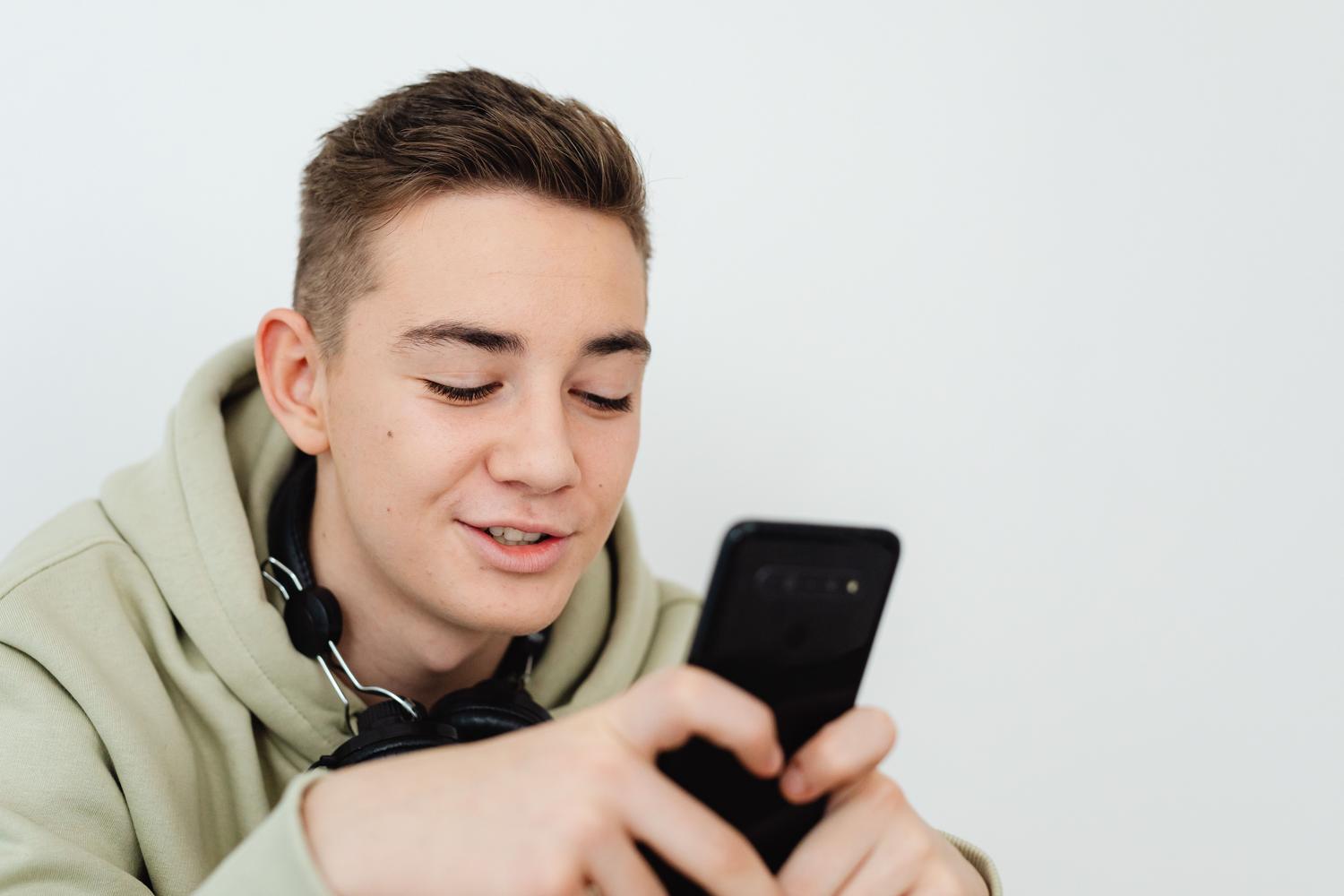 Hombre joven sonriendo mientras usa su smartphone, ilustrando la experiencia positiva de buscar pareja online.