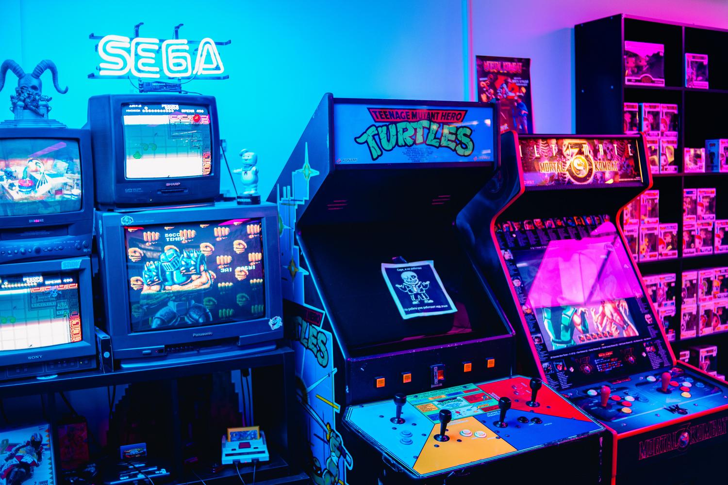 Vista general de un salón recreativo retro con pantallas CRT y luces de neón, contextualizando la época dorada de los videojuegos.
