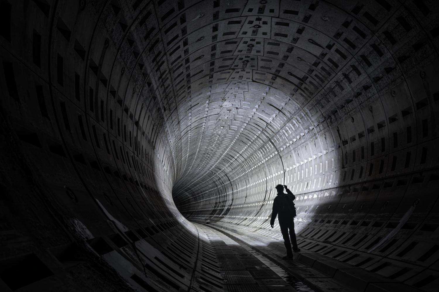 Silueta misteriosa en un túnel futurista oscuro, evocando la tensión, el sigilo y la claustrofobia de Metroid Dread.