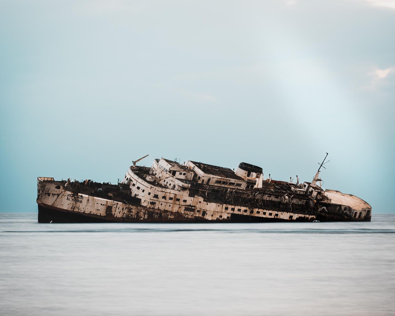 Restos de un barco oxidado y olvidado flotando en aguas tranquilas, representando la misteriosa nave a la deriva.