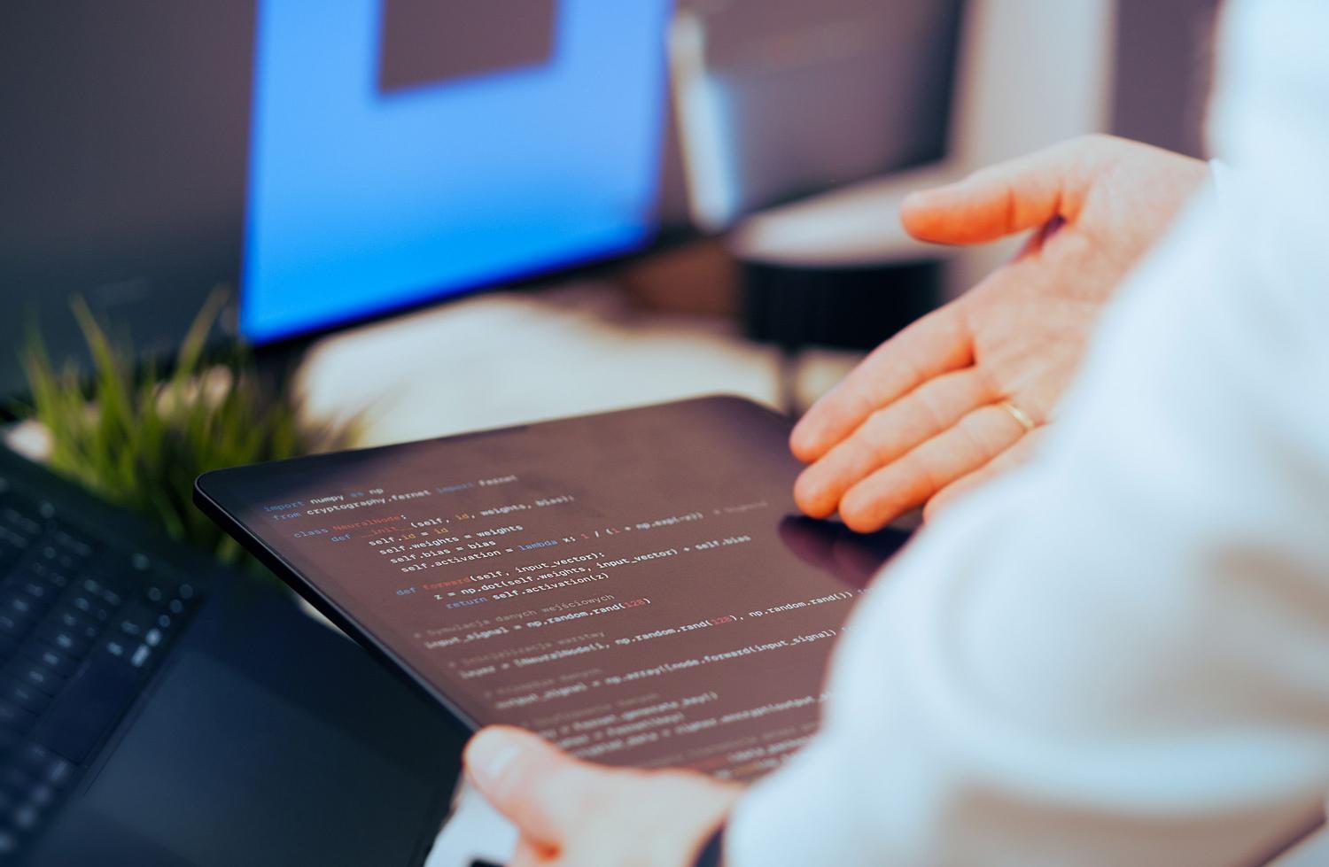 Desarrollador de software revisando líneas de código en una tablet, ilustrando el rol del arquitecto humano que supervisa a un agente de IA.