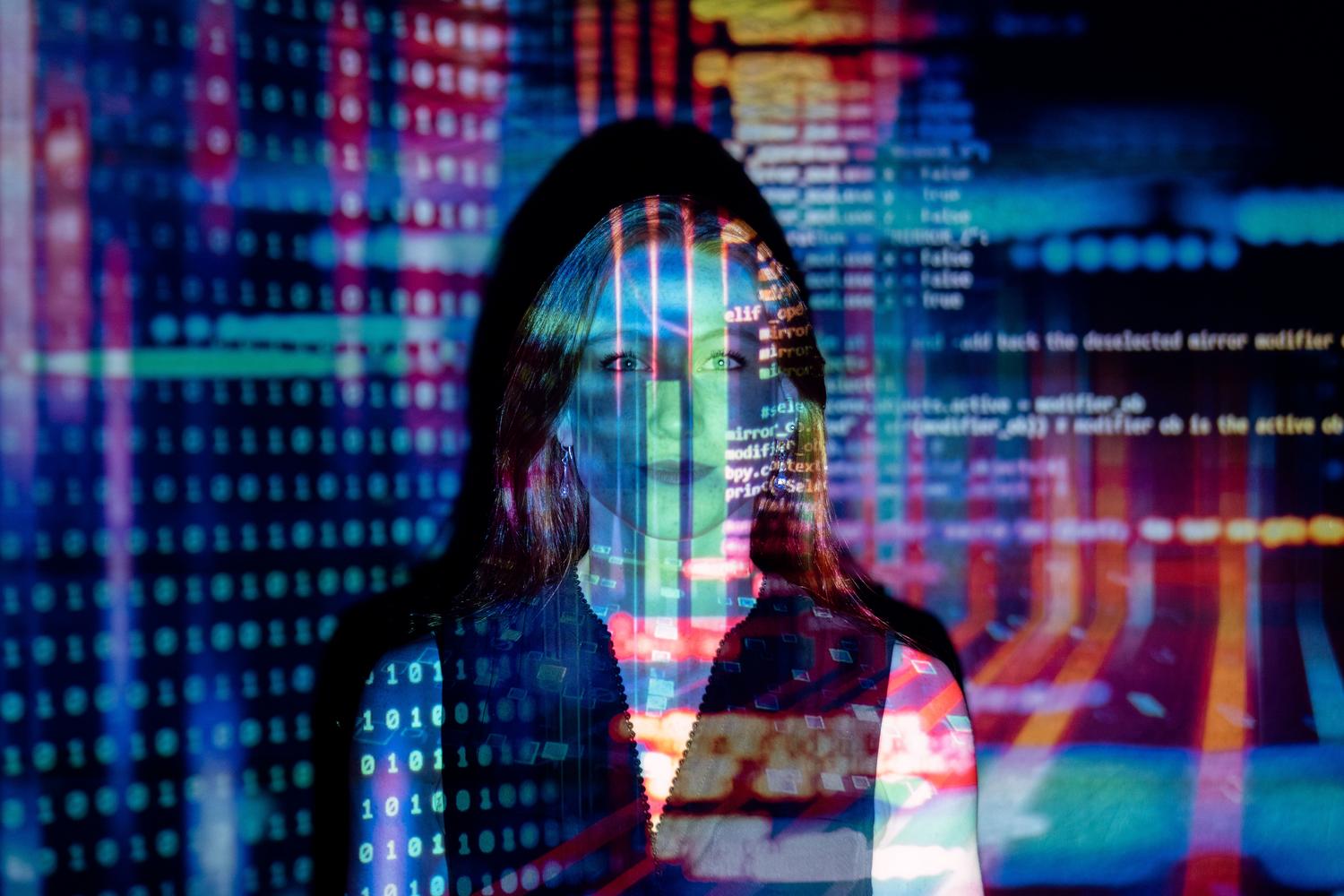 Imagen conceptual de una mujer con proyecciones de código digital sobre su rostro, representando la fusión entre la inteligencia humana y la artificial.