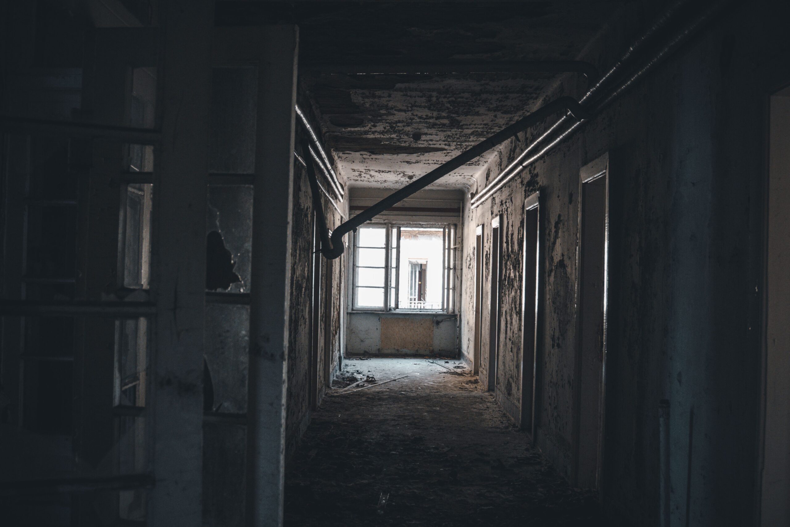 Pasillo abandonado y lúgubre en un edificio en decadencia, evocando los misterios y puzles de la comisaría.