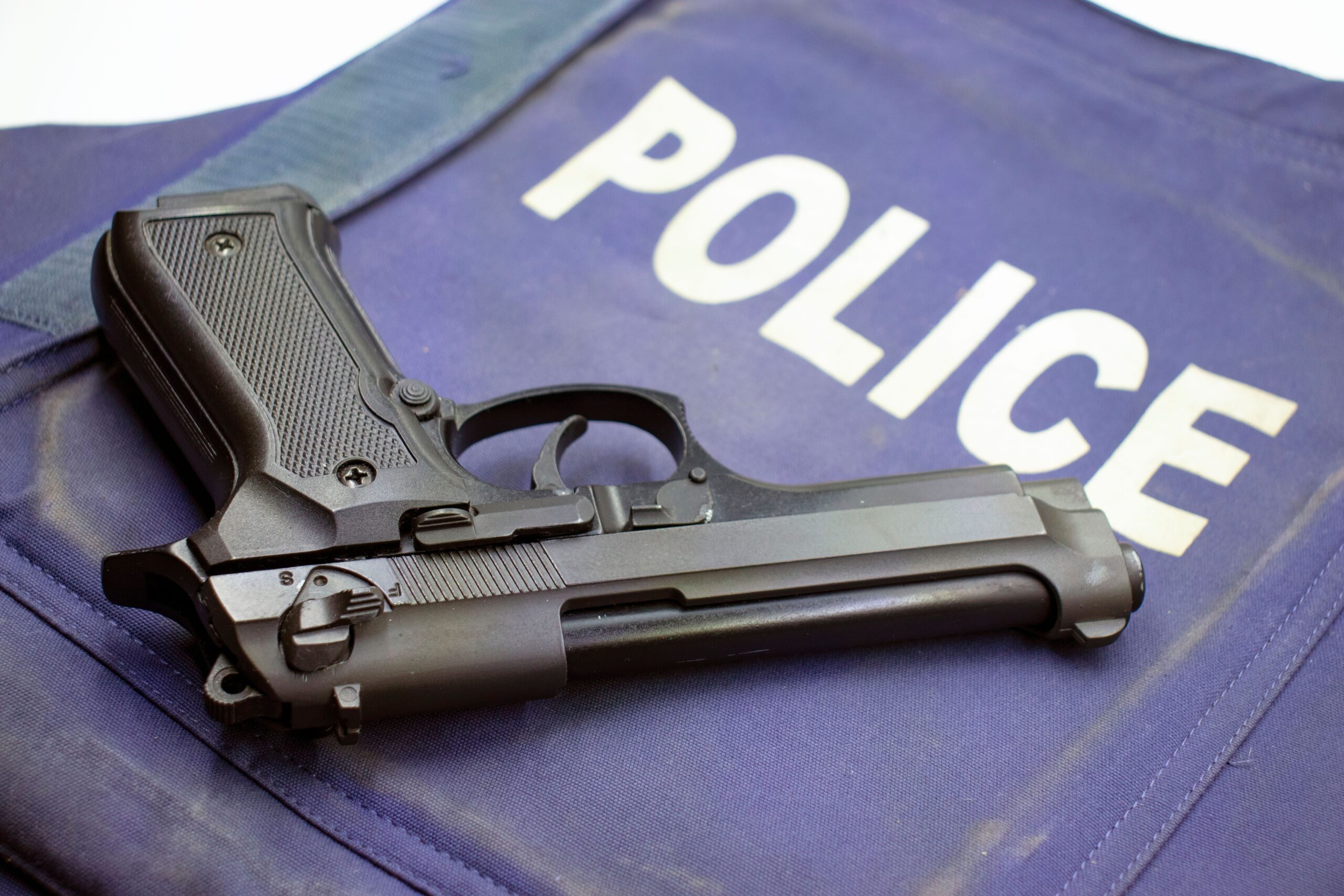 Pistola negra sobre un chaleco policial, ilustrando el arsenal y equipamiento de supervivencia.