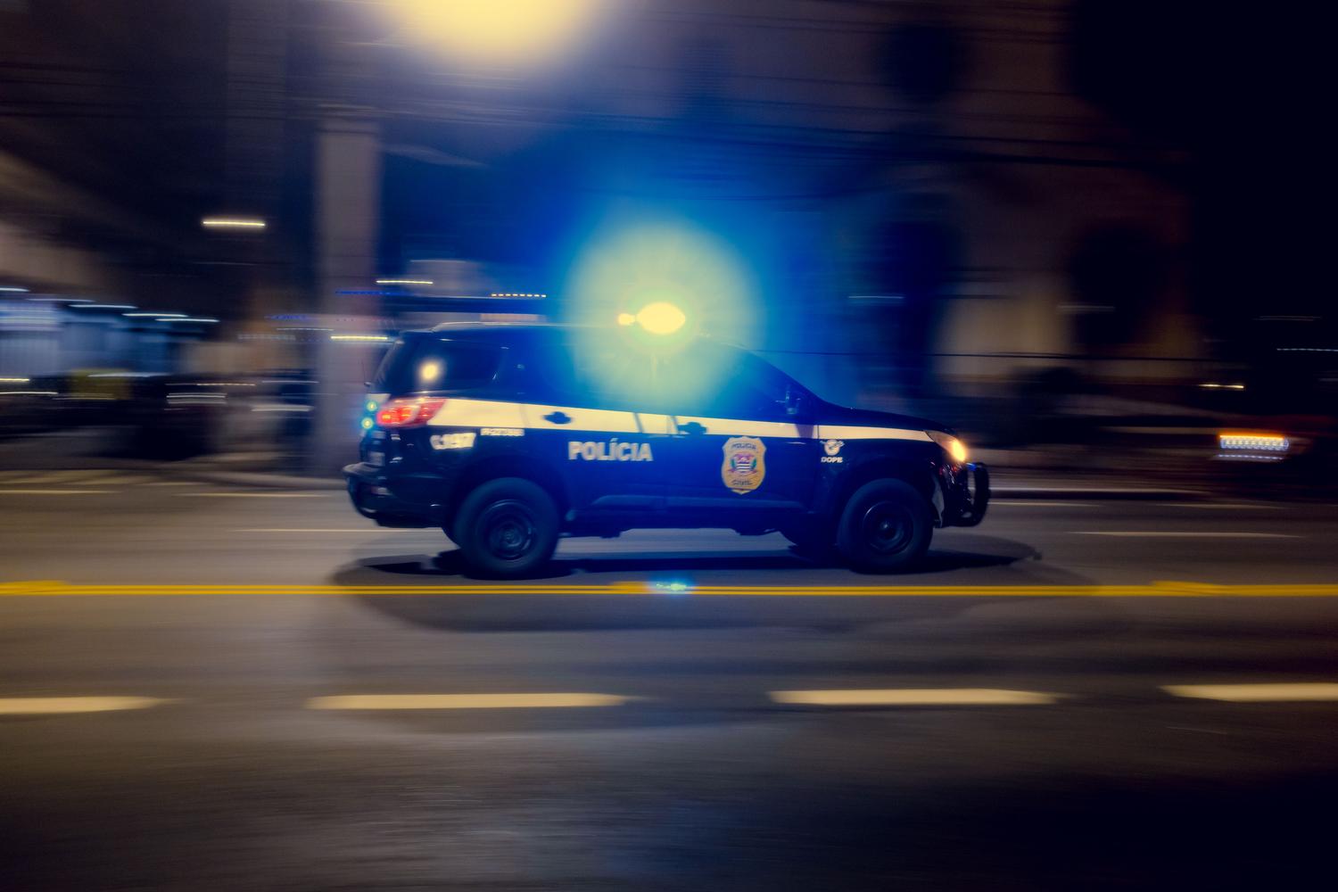 Coche de policía circulando a alta velocidad por la ciudad de noche con luces encendidas, ilustrando las persecuciones y el sistema de estrellas.