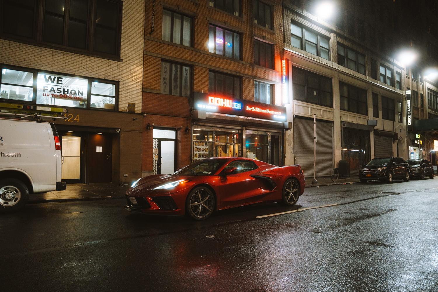 Coche deportivo rojo de lujo estacionado en una calle urbana iluminada de noche, representando los vehículos emblemáticos de la saga.