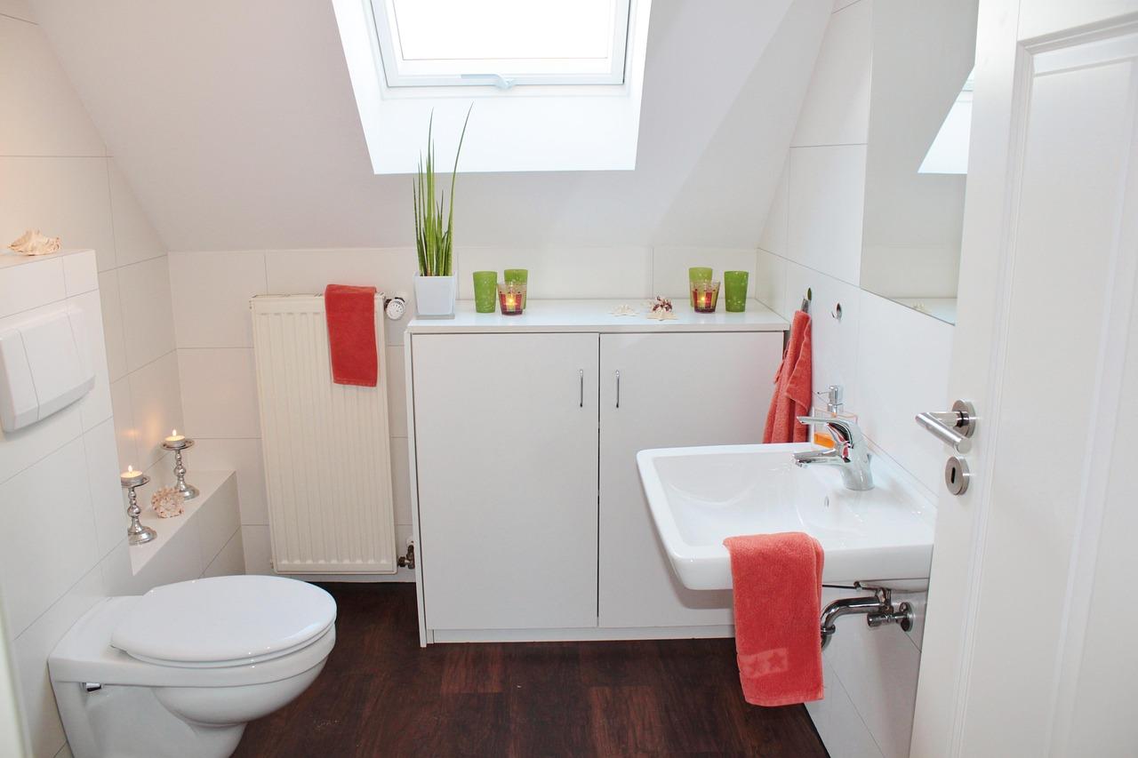 Baño moderno y limpio con azulejos blancos y sanitarios brillantes, representando el resultado de la desinfección.
