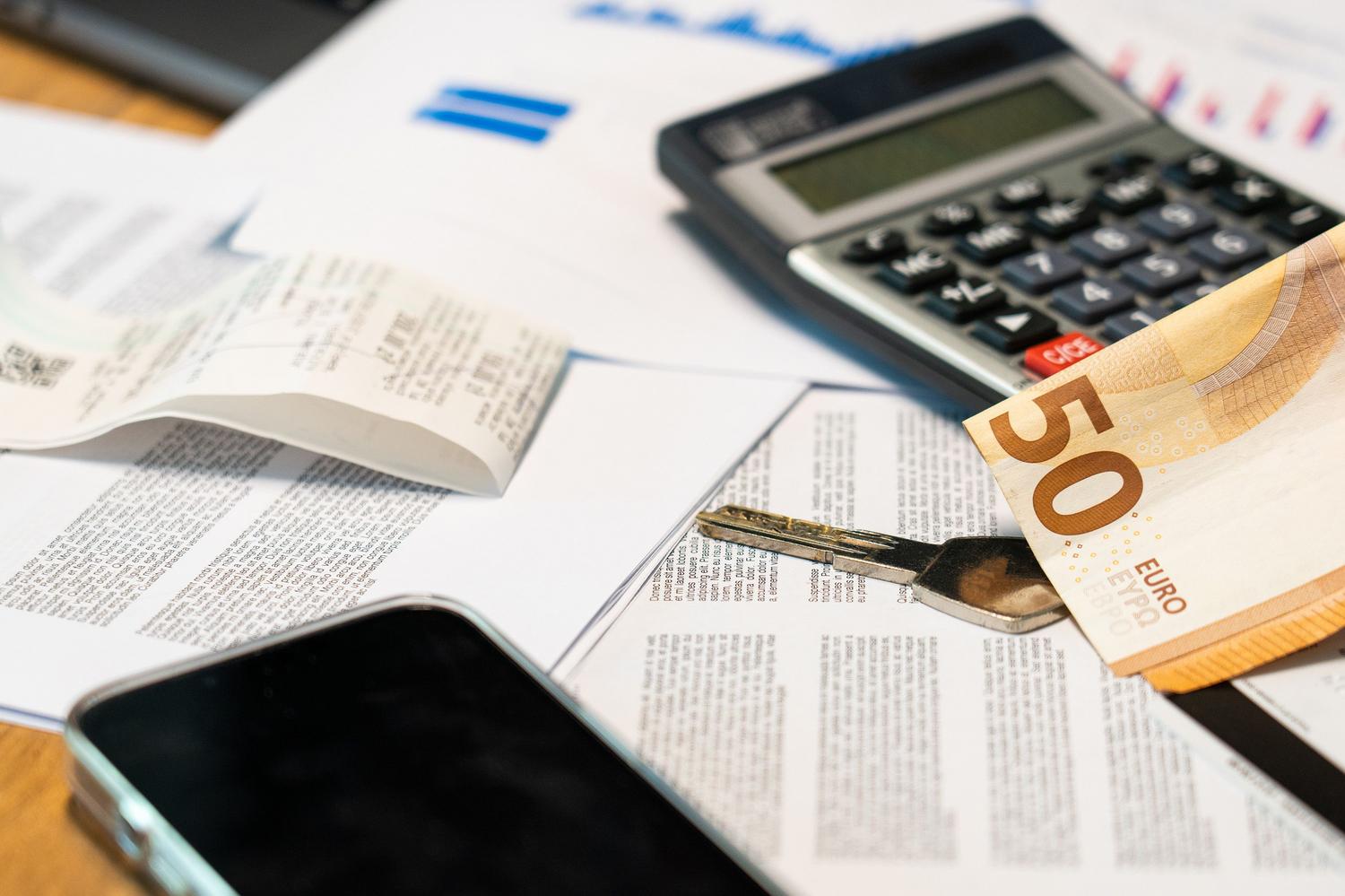 Vista cenital de herramientas financieras: calculadora, móvil y billetes de euro.