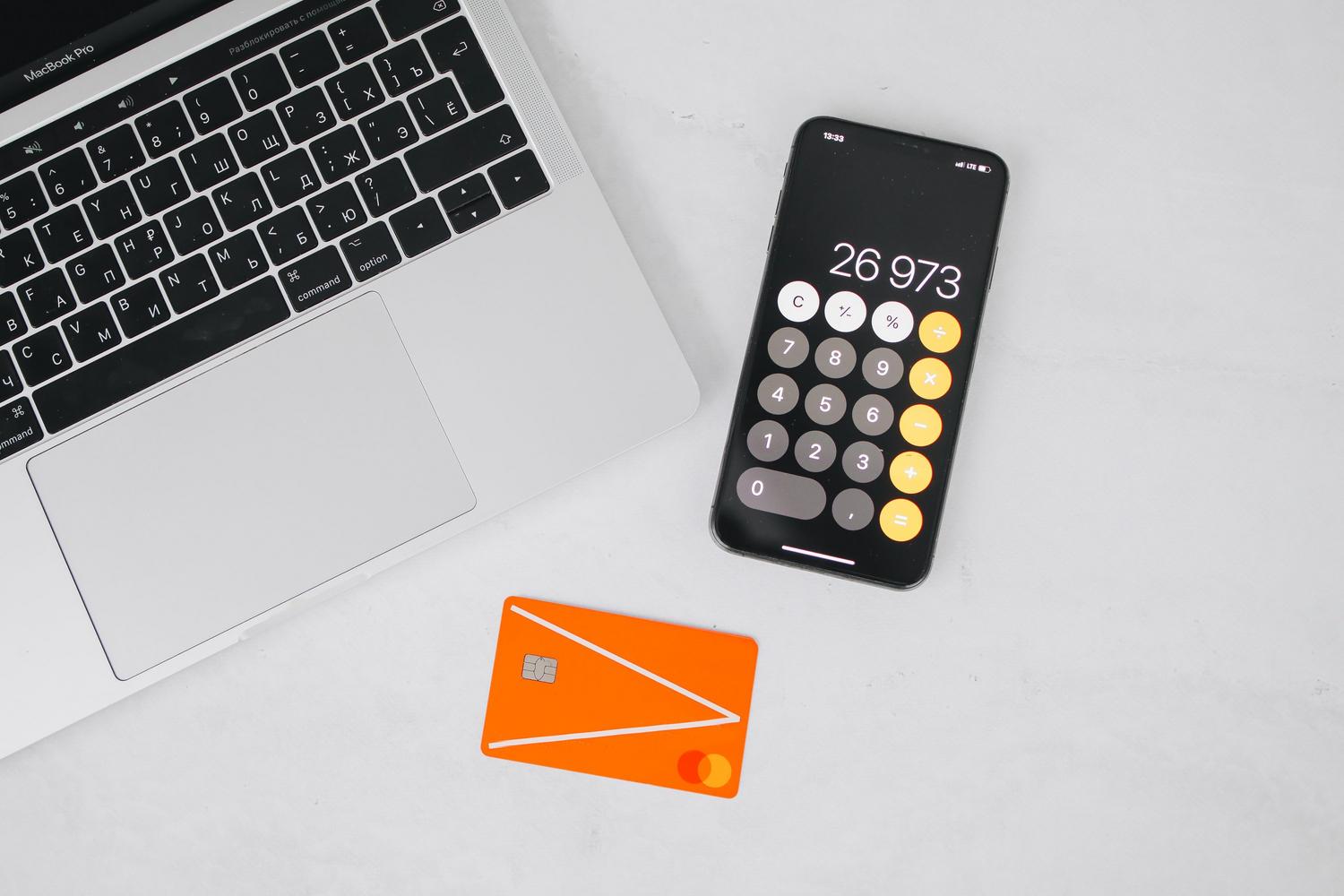 Composición de ordenador portátil, smartphone y tarjeta de crédito sobre fondo blanco.