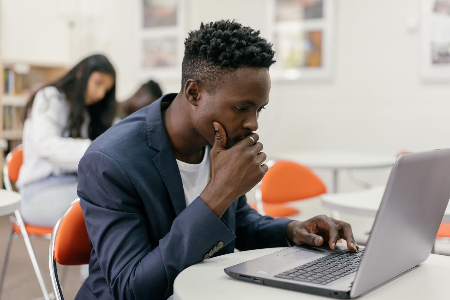 Estudiante enfocado preparando el examen de certificación CISM mediante un ordenador en un entorno de estudio moderno.