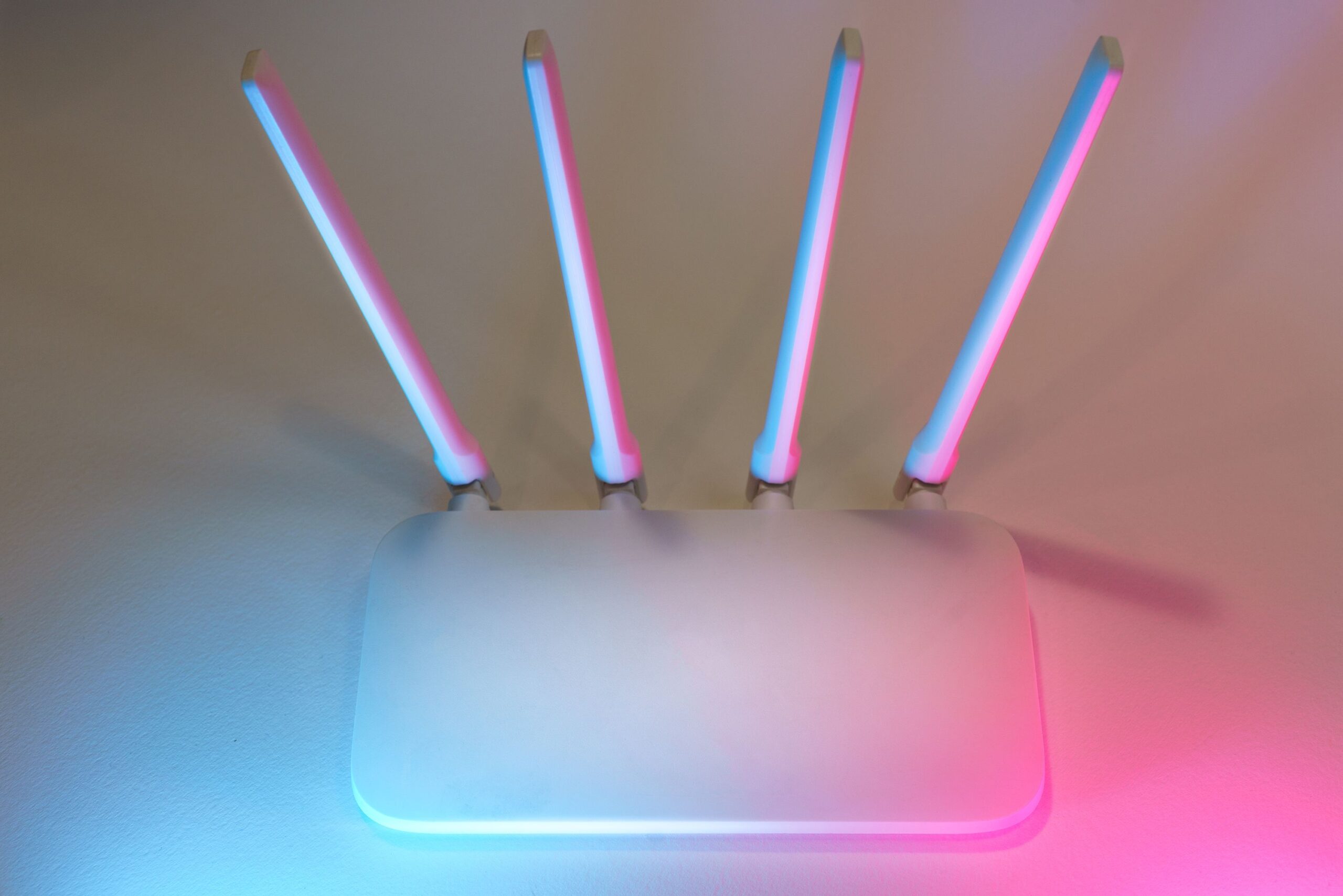 Router inalámbrico moderno de color blanco con cuatro antenas y luces decorativas en tonos azul y rosa, representando la tecnología de red avanzada.