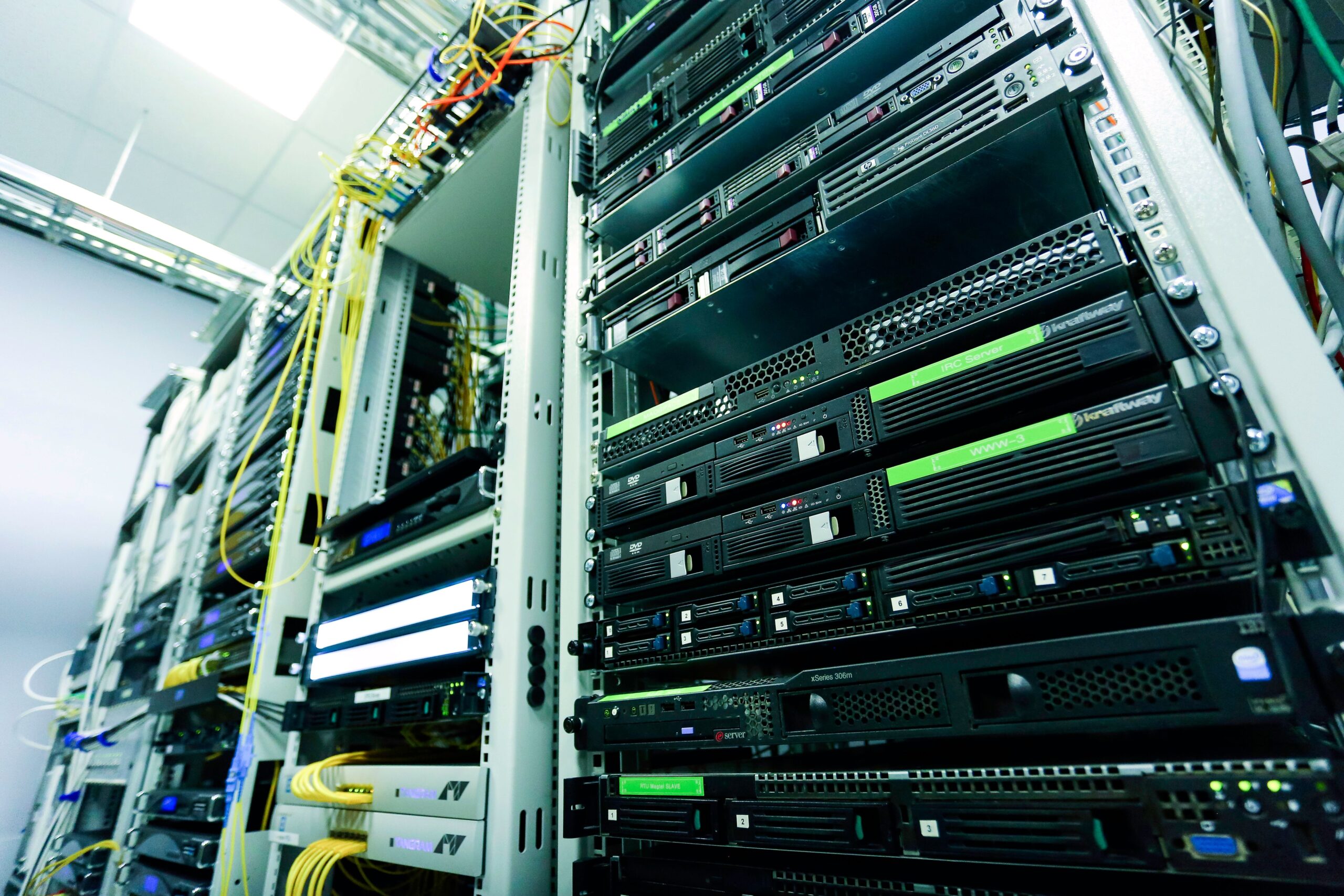 Racks de servidores en un centro de datos con cableado complejo y luces LED, representando la infraestructura de servidores VPN externos.