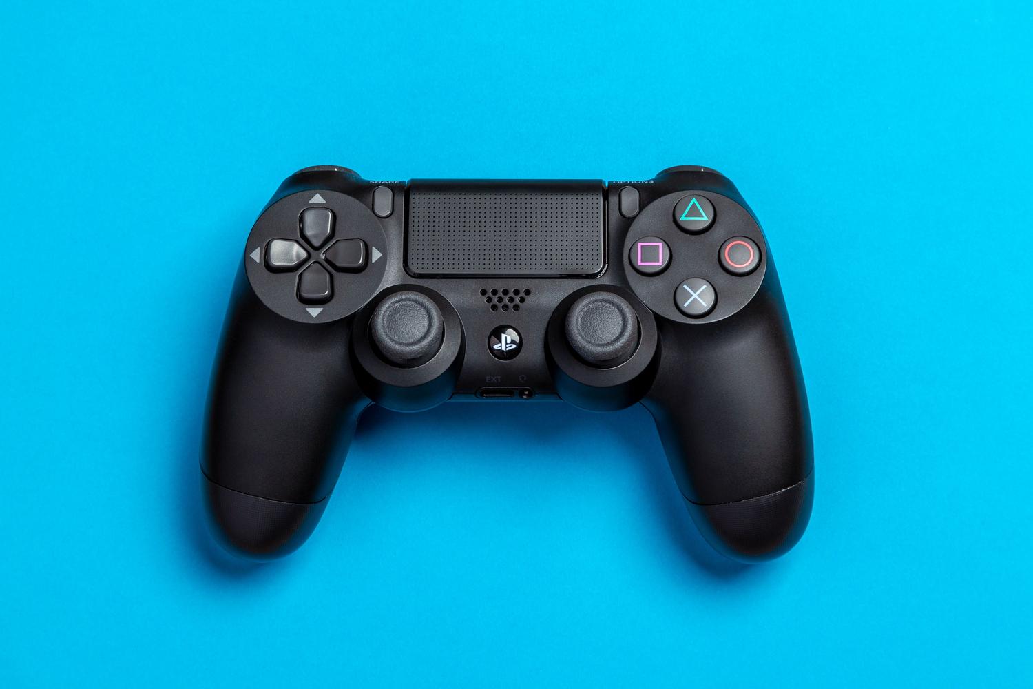 Mando negro de PS4 centrado sobre un fondo azul eléctrico.