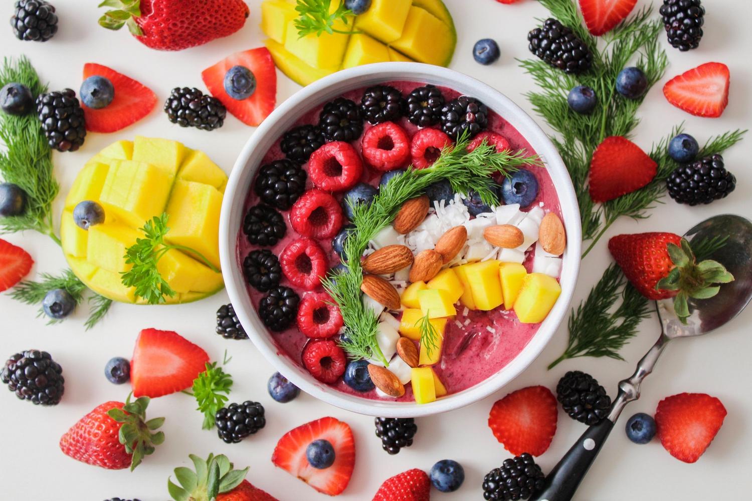 Bowl de smoothie saludable con bayas, mango y almendras, rico en polifenoles y vitamina E.