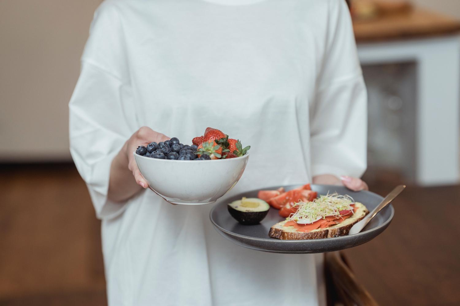 Desayuno antioxidante compuesto por un bol de bayas frescas y tostadas de aguacate.