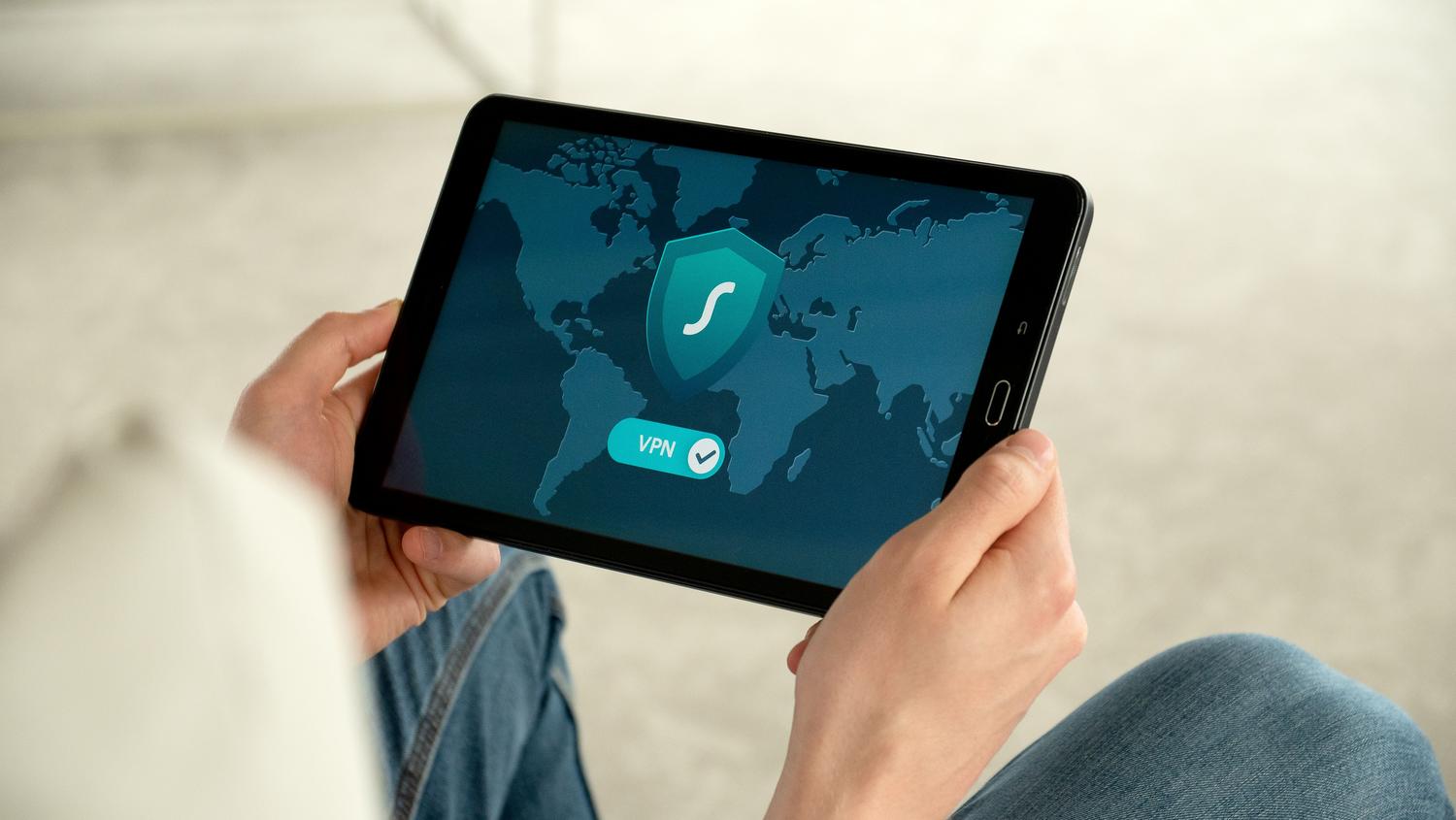 Persona utilizando una tableta con una conexión VPN activa para navegar de forma segura en redes públicas.