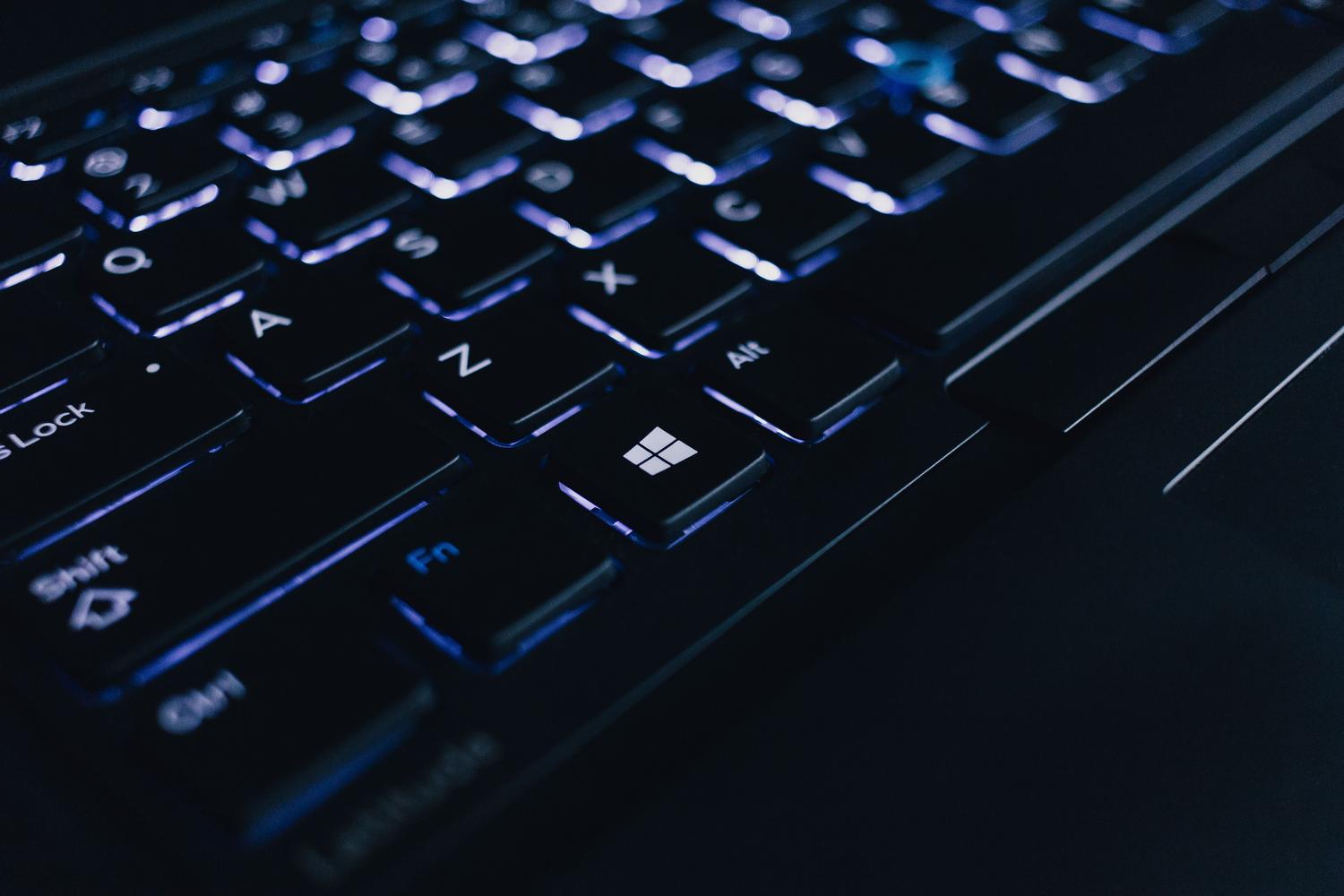 Primer plano de un teclado de laptop iluminado, sugiriendo la interacción del usuario con el sistema operativo Windows.