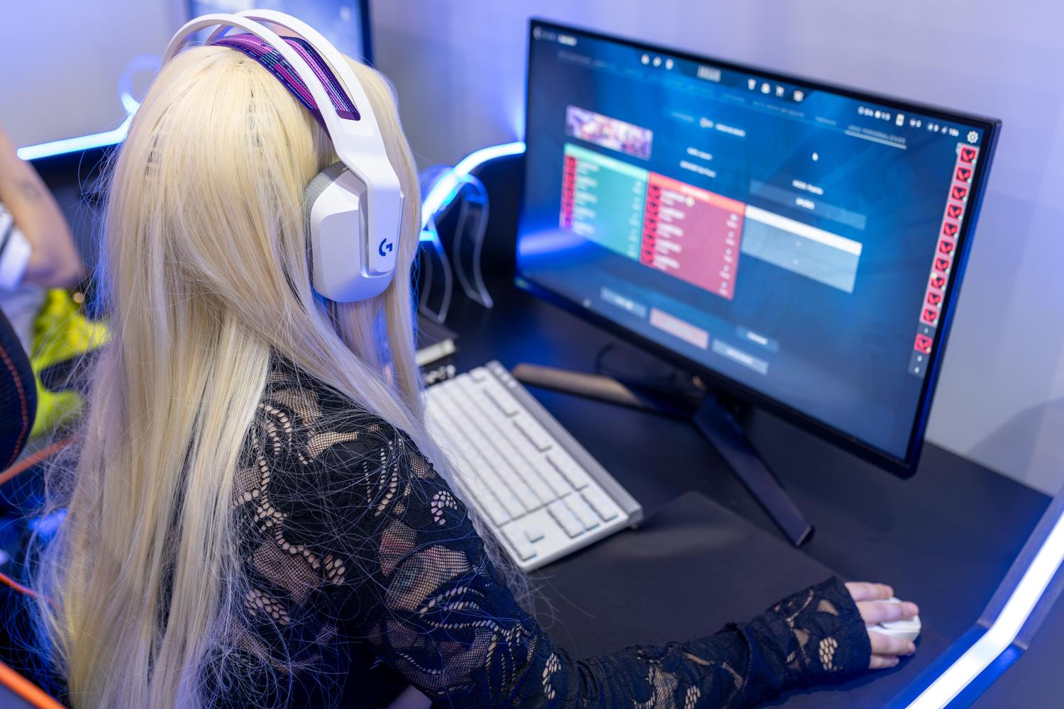 Joven gamer concentrada usando auriculares en su PC, ilustrando la inmersión en los videojuegos.