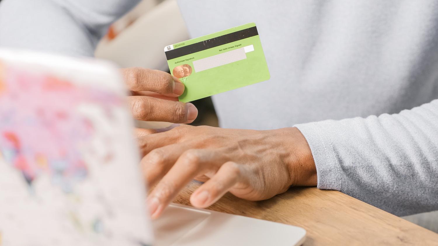 Primer plano de una persona realizando una compra online con tarjeta de crédito, relacionando el proceso de adquisición de claves.