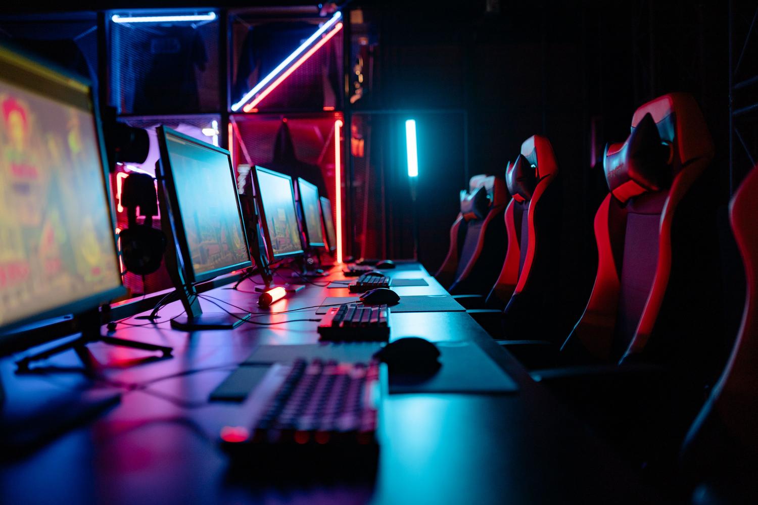 Habitación de gaming inmersiva con luces de neón y computadoras, evocando la cultura gamer actual.