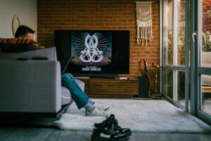 Persona relajada en el sofá de su salón frente a un televisor inteligente, representando la gestión de listas de seguimiento de Google TV