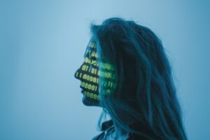 Silueta de mujer con código binario proyectado en su rostro simbolizando la máscara digital de la IA