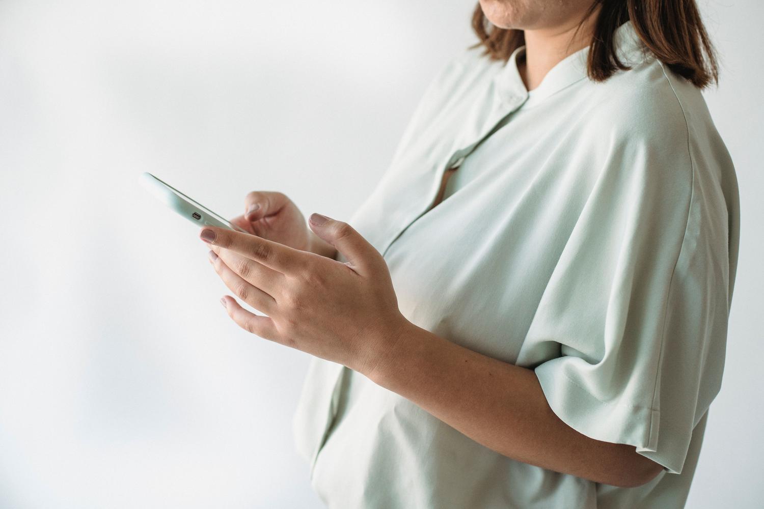 Primer plano de una persona interactuando con un smartphone moderno sobre un fondo blanco minimalista, resaltando la limpieza del software.
