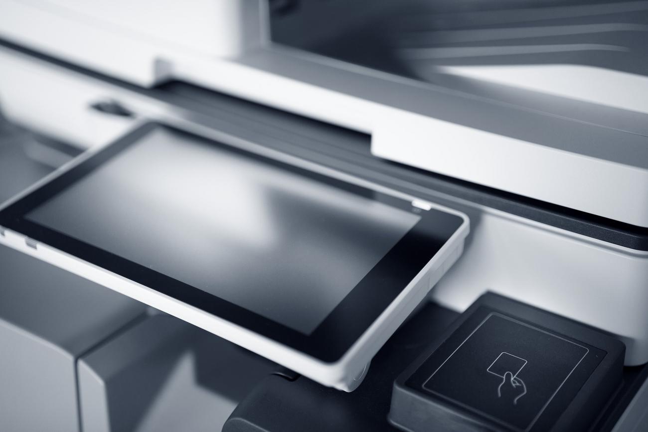Primer plano de la interfaz táctil de una impresora multifunción moderna con lector NFC.