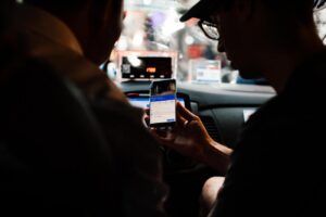 Persona usando un smartphone con una app de rideshare dentro de un taxi por la noche
