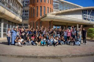 Grupo diverso de estudiantes universitarios celebrando frente a un campus moderno, representando la experiencia internacional de estudiar fuera.