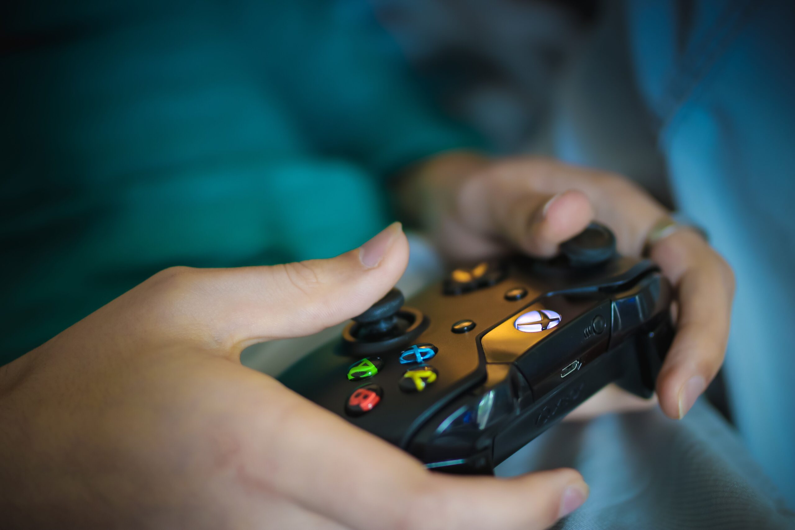 Primer plano de unas manos sosteniendo un mando de consola moderno, elemento esencial para interactuar con las misiones de un videojuego.