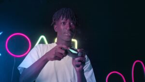 Joven jugador concentrado en una sesión de videojuegos en un entorno con luces de neón, representando la inmersión en el mundo virtual.