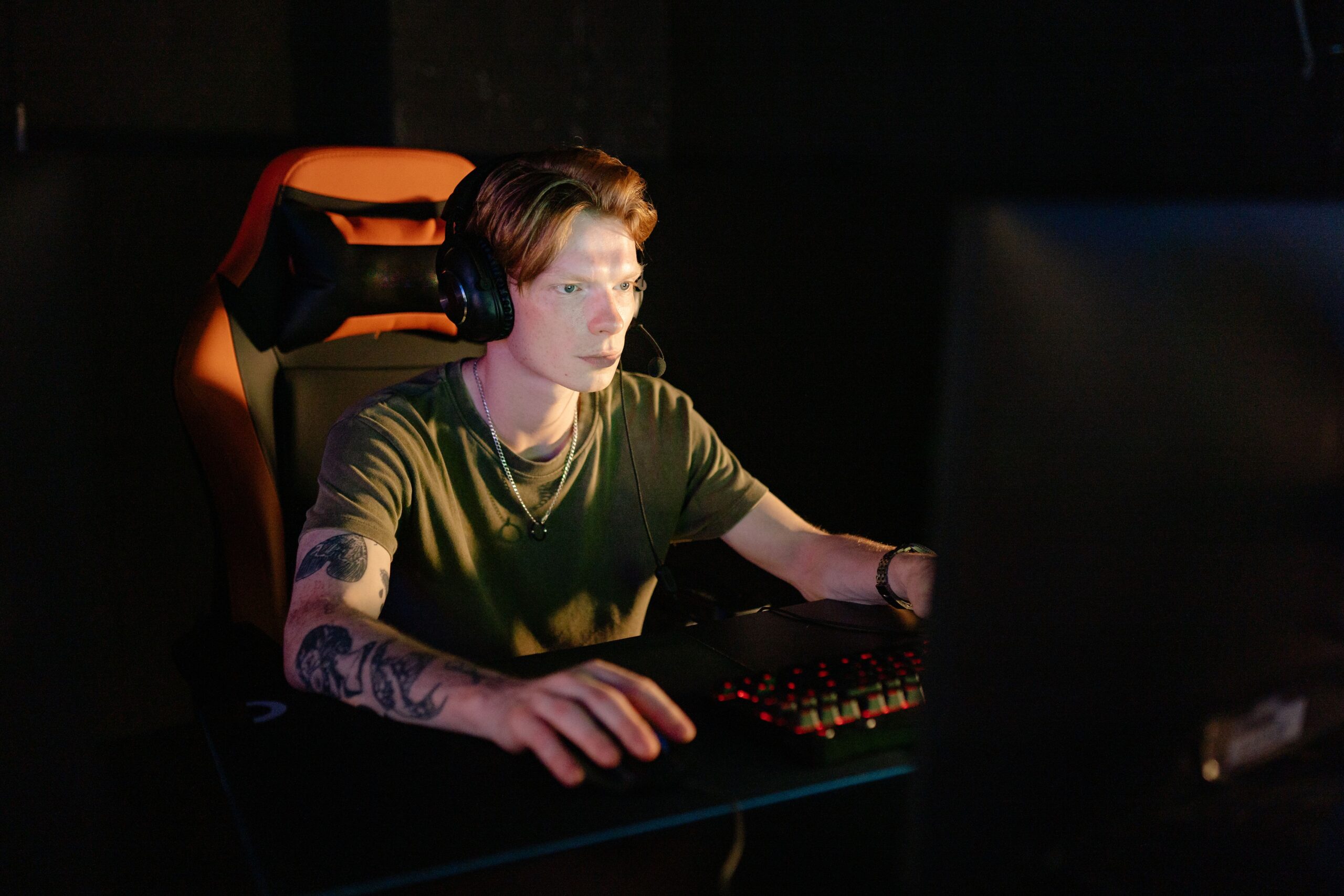 Jugador profesional utilizando un asiento ergonómico y auriculares, reflejando la gestión del tiempo y las largas sesiones de juego para completar el 100% del contenido.