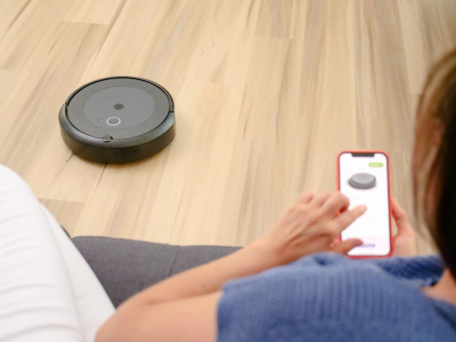 Persona controlando la configuración del modo inteligente Smart Plan de un robot aspirador a través de una aplicación móvil en un salón moderno.