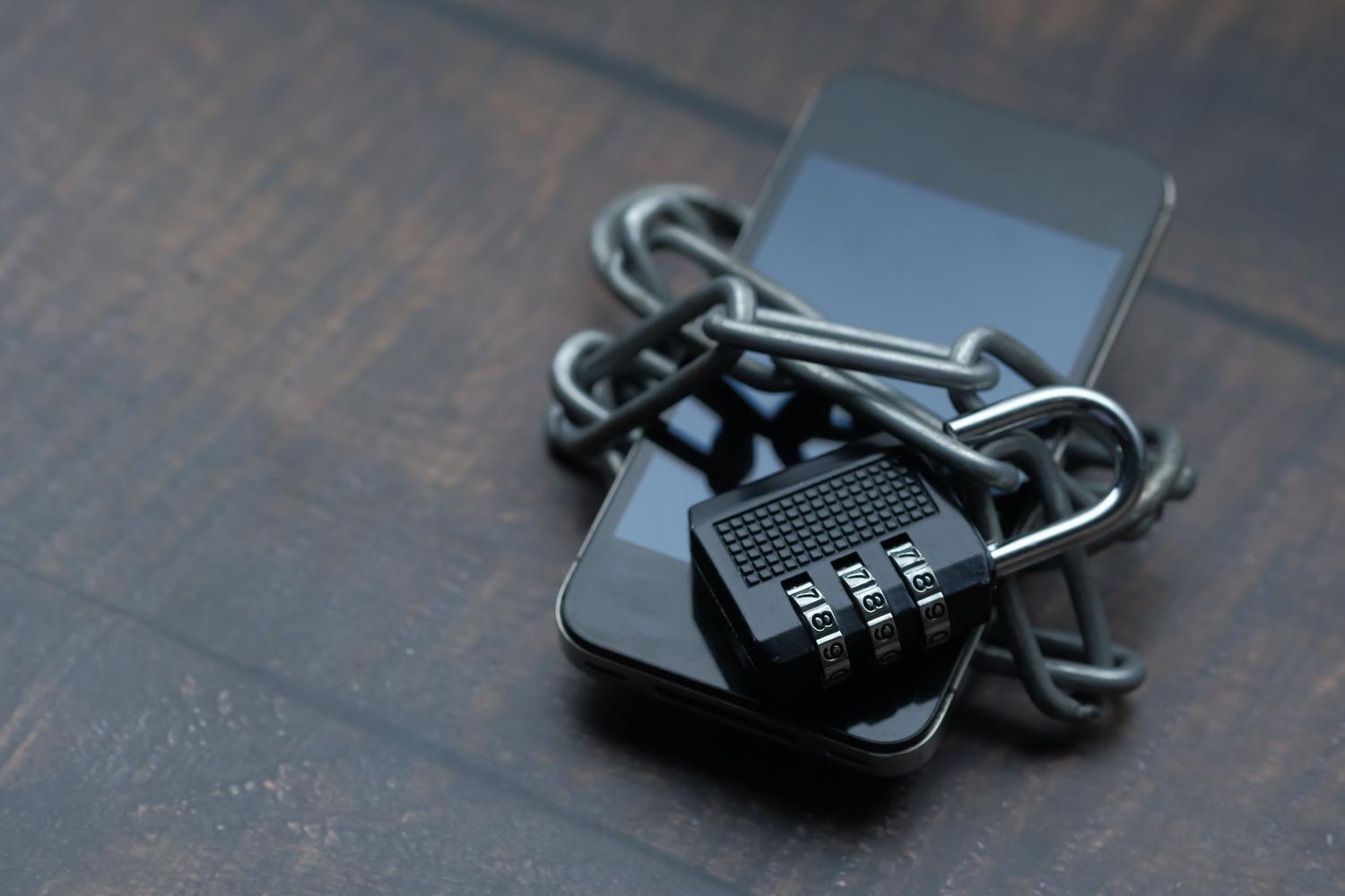 Primer plano de un smartphone envuelto en una cadena con un candado, simbolizando la seguridad digital