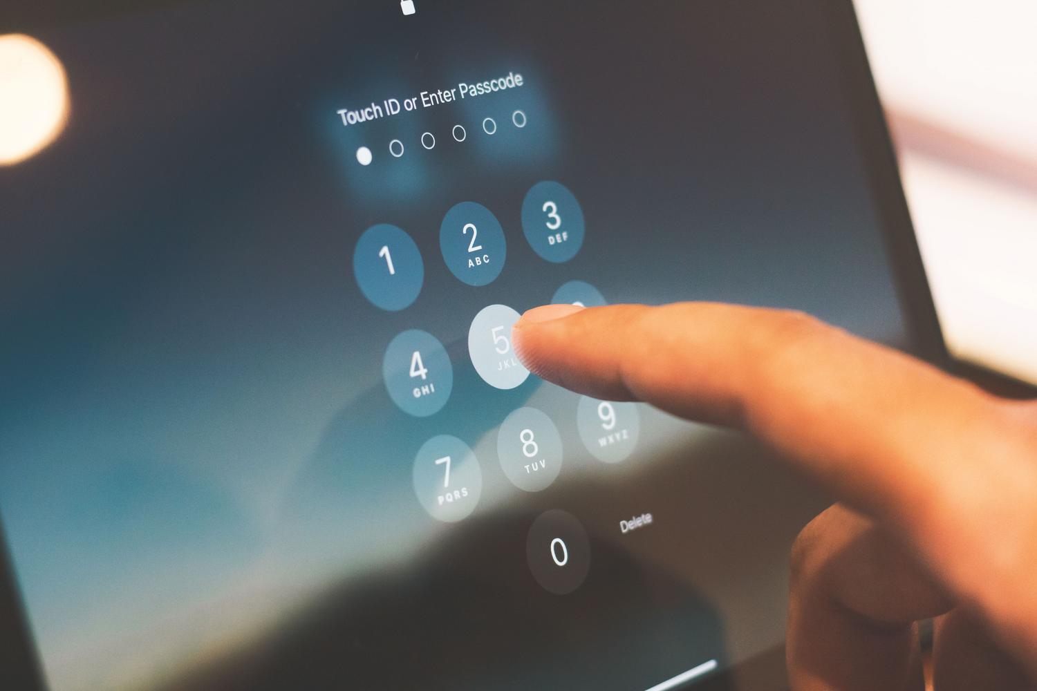 Detalle de un dedo introduciendo un código de seguridad en la pantalla de un teléfono móvil
