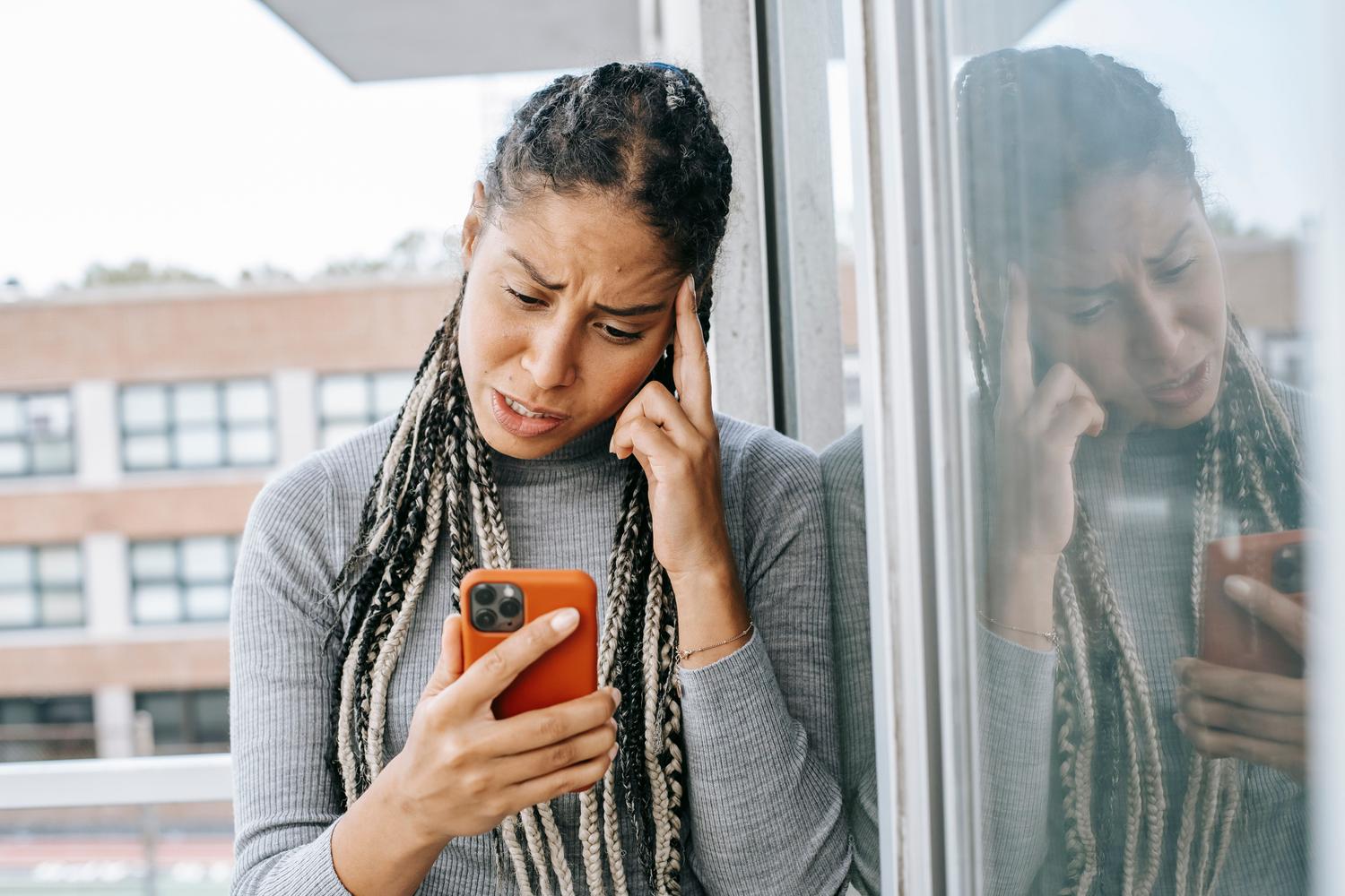 Mujer preocupada mirando la pantalla de su móvil, reflejando la angustia de perder el acceso a sus cuentas