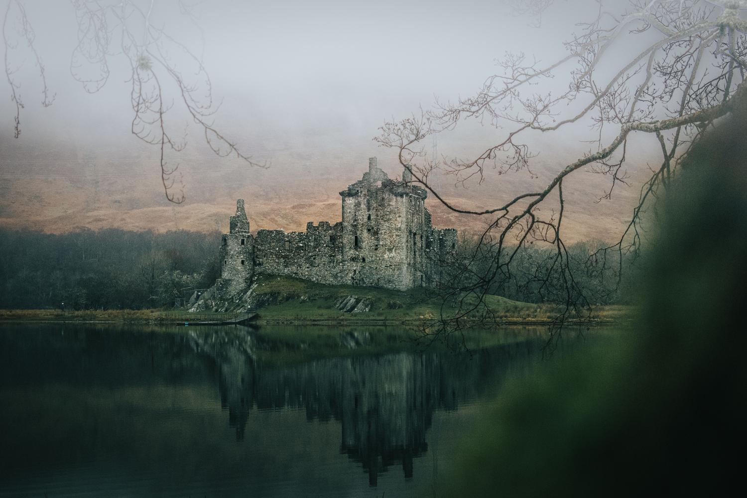 Castillo medieval envuelto en niebla, representando los escenarios sombríos y realistas del nuevo juego de HoYoverse.