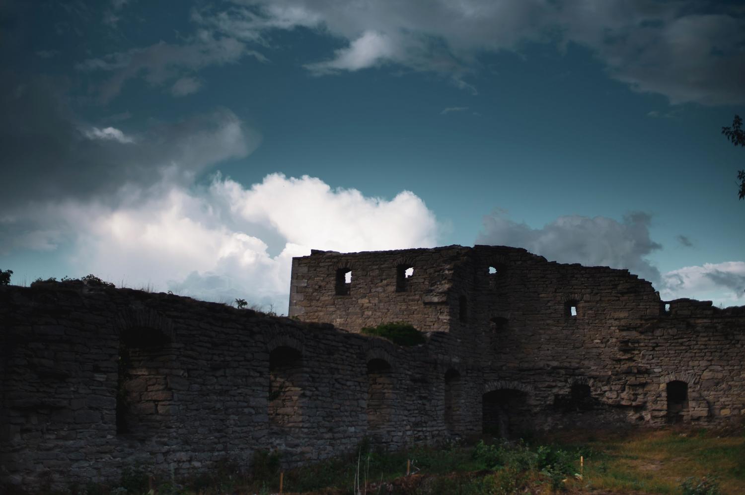 Ruinas de un castillo antiguo bajo un cielo nublado y dramático, reflejando la estética de Nodus Fall.