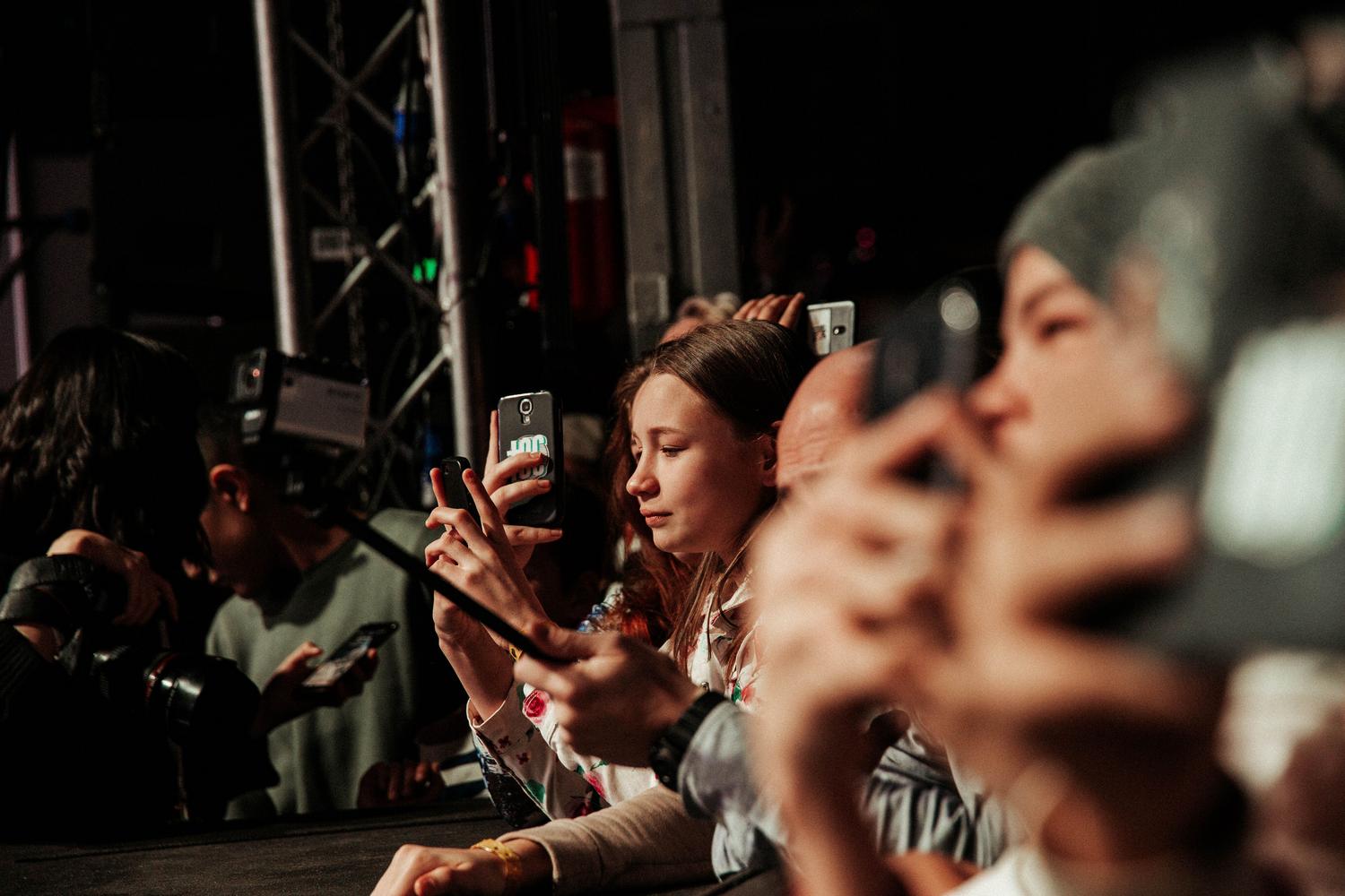 Fans capturando la actuación de su ídolo con smartphones, ilustrando la interacción digital del stan actual.