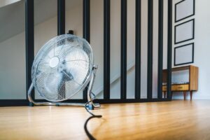 Ventilador de pie metálico sobre suelo de madera en una habitación moderna sin personas, listo para funcionar