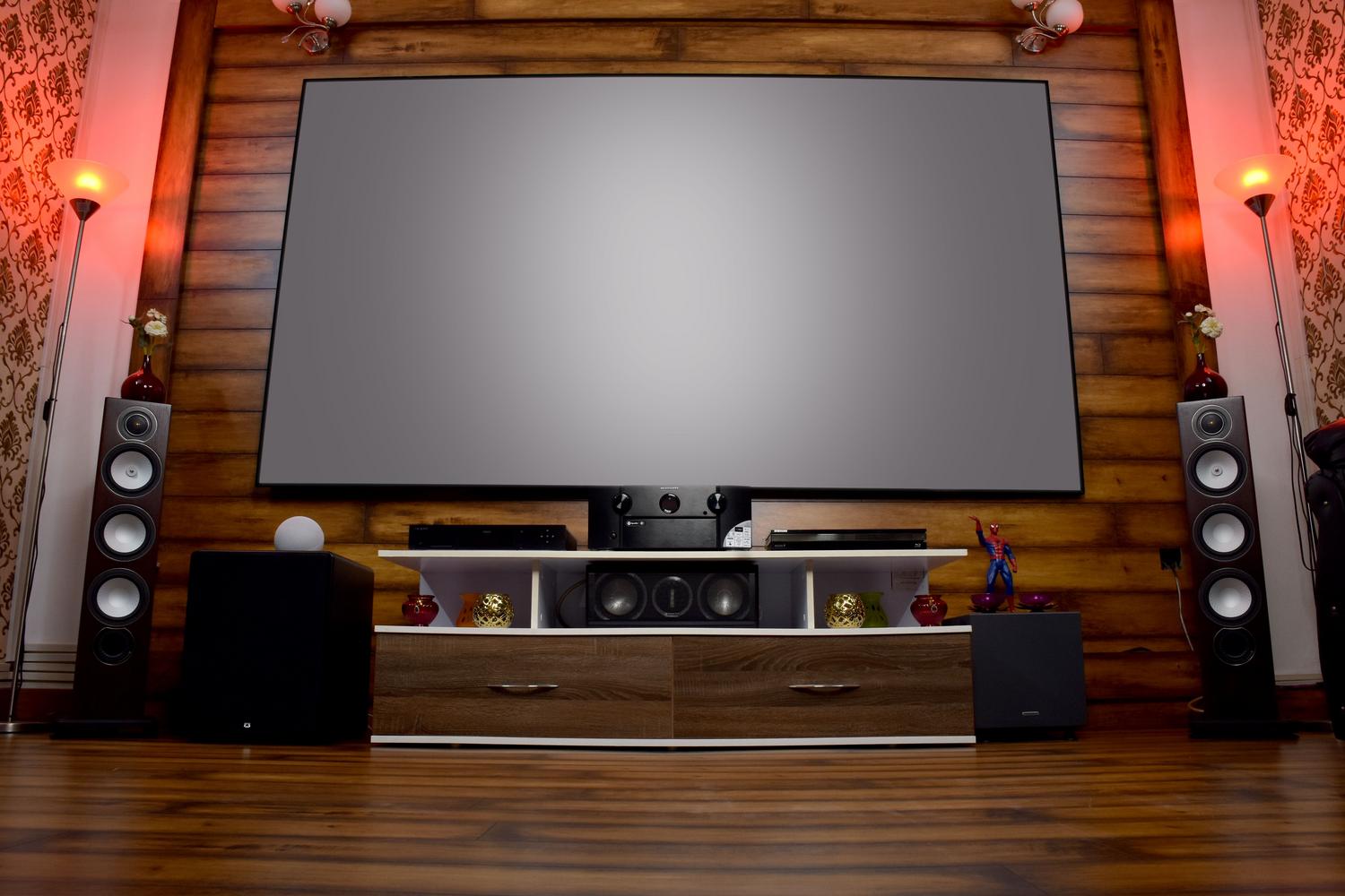 Salón moderno con sistema de cine en casa, pantalla grande y equipo de sonido integrado para una experiencia de alta fidelidad.