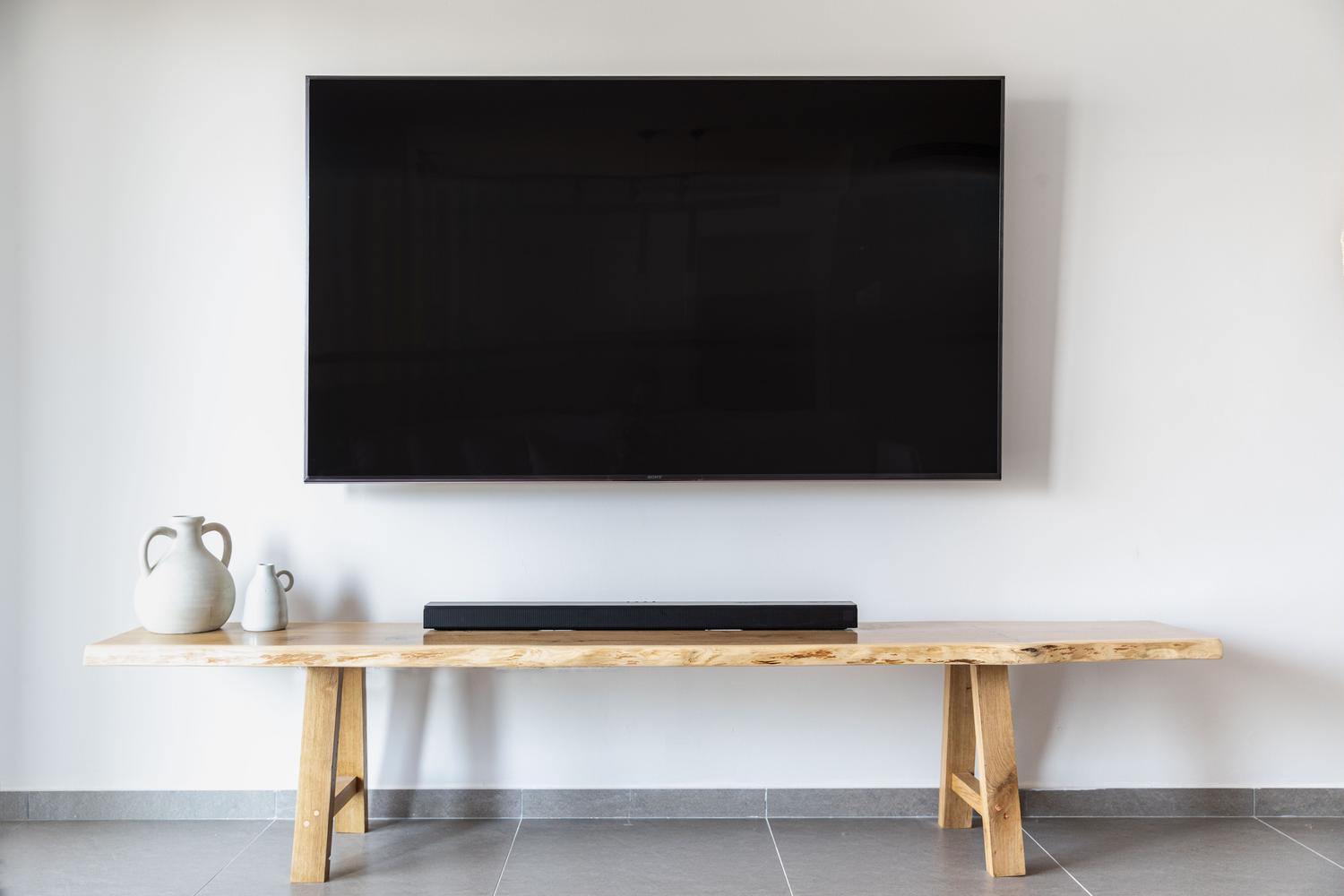 Salón minimalista con televisor de pantalla plana montado en la pared, simbolizando la simplificación del cableado.