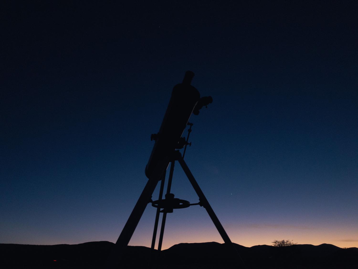 Silueta de un telescopio contra el cielo del crepúsculo, ideal para la observación astronómica