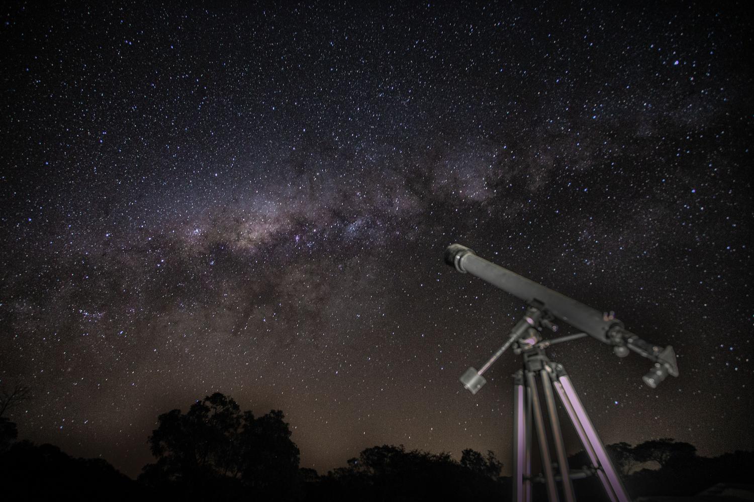 Telescopio astronómico apuntando hacia la Vía Láctea en una noche despejada