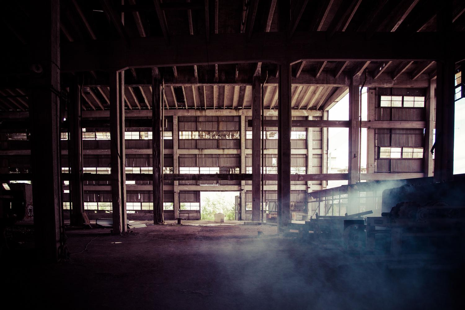 Interior de un almacén abandonado y oscuro, representando los búnkeres subterráneos procedurales del juego.