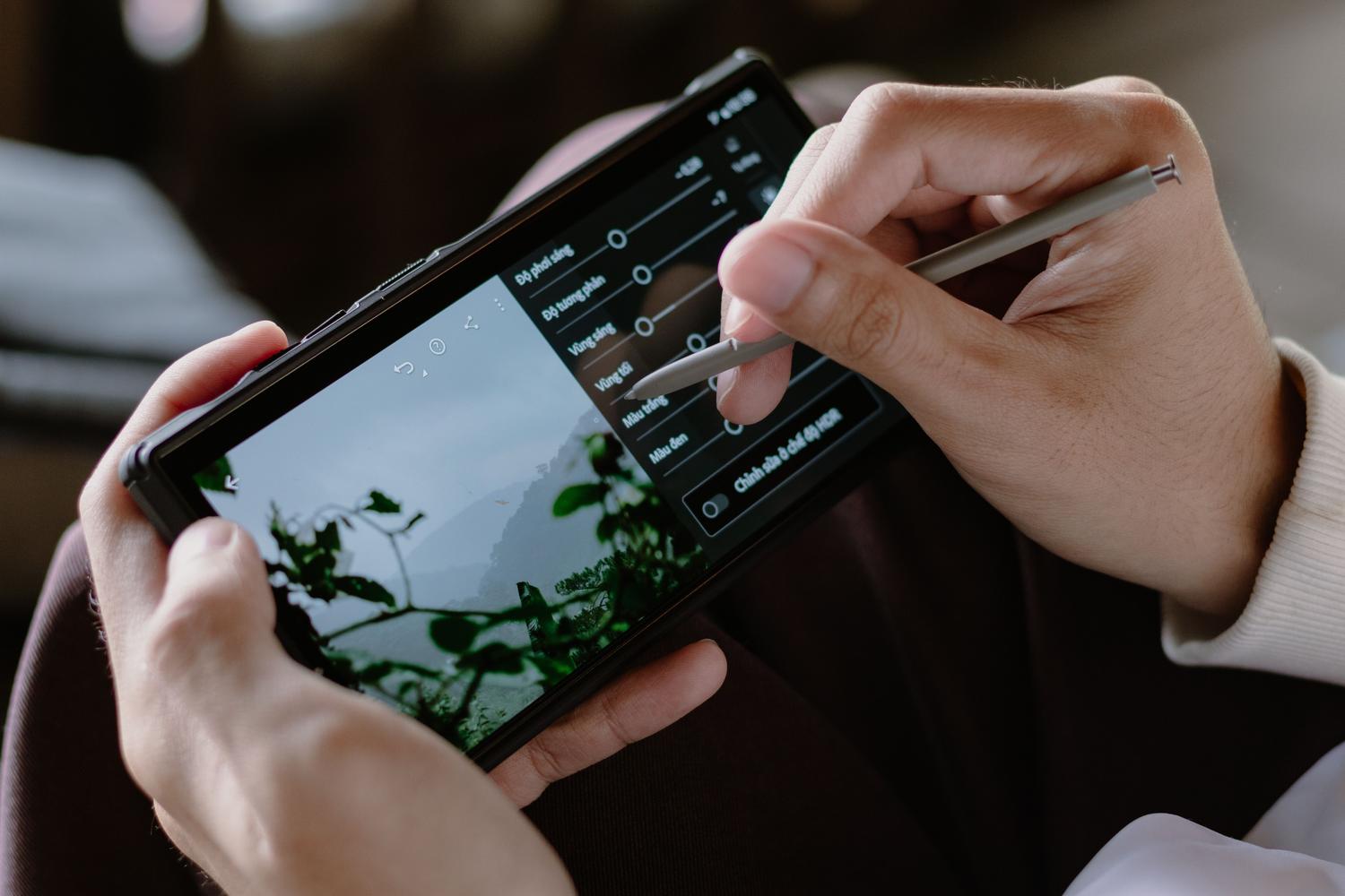 Primer plano de una persona editando fotografías en un dispositivo móvil, representando las herramientas de AI Enhance y Magic Eraser.